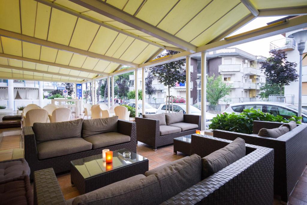d'une terrasse avec des canapés, des tables et des fenêtres. dans l'établissement Hotel Aurora, à Lignano Sabbiadoro
