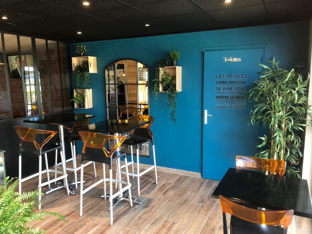 un restaurant avec des tables et des chaises noires et un mur bleu dans l'établissement Camping les Acacias, à Fréjus