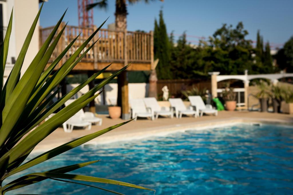 une piscine avec des chaises longues blanches et une terrasse dans l'établissement Camping les Acacias, à Fréjus