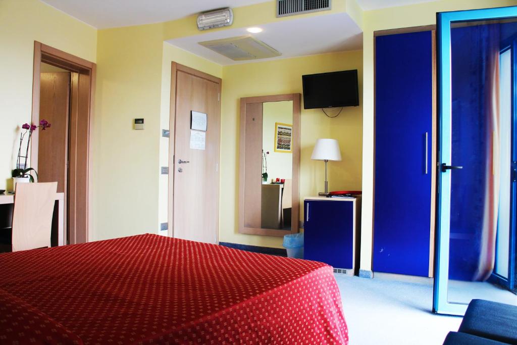 une chambre avec un lit rouge et une porte bleue dans l'établissement Hotel Cristallo, à Lignano Sabbiadoro
