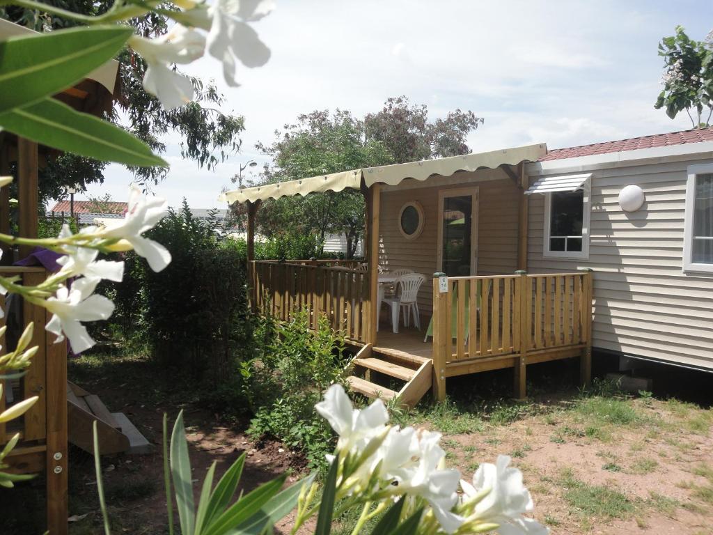 une petite maison avec un porche et une terrasse dans l'établissement Camping les Acacias, à Fréjus