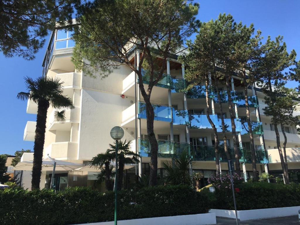 un bâtiment blanc avec des palmiers devant dans l'établissement Hotel Bellevue, à Lignano Sabbiadoro