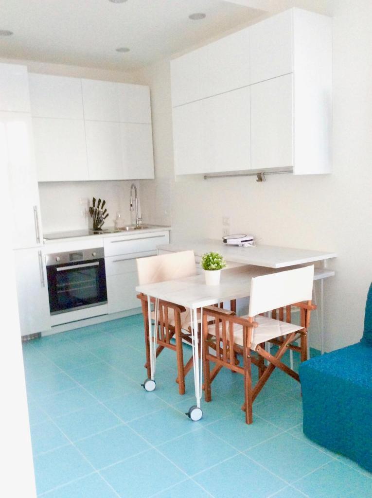 une cuisine avec des armoires blanches et une table et des chaises dans l'établissement Apartment on the sea, à Cagliari