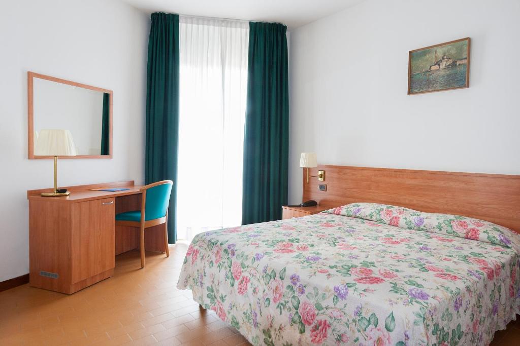 une chambre d'hôtel avec un lit, un bureau et une fenêtre dans l'établissement Regent's Hotel, à Lido di Jesolo