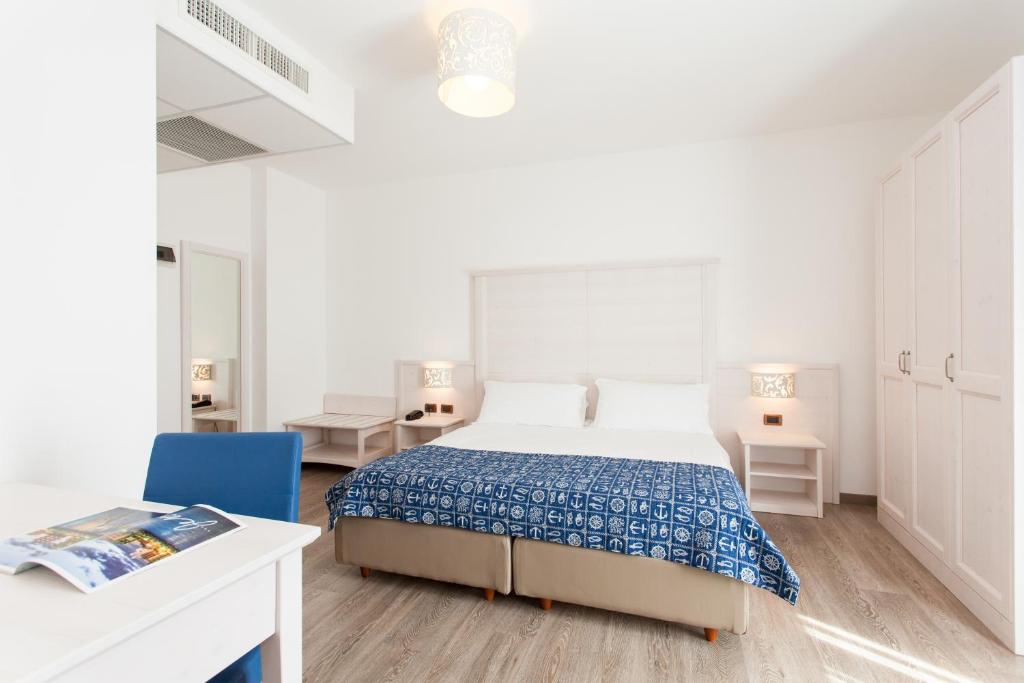 une chambre blanche avec un lit et une chaise bleue dans l'établissement Regent's Hotel, à Lido di Jesolo