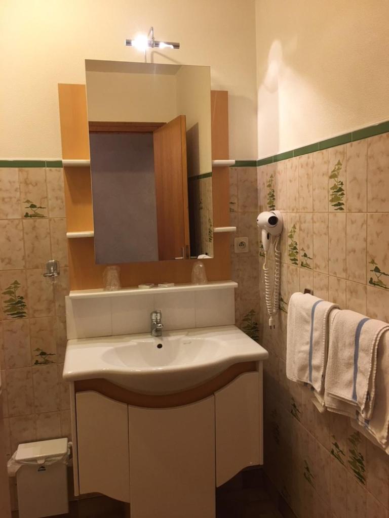 une salle de bain avec un lavabo, un miroir et des serviettes dans l'établissement Hôtel Les Soldanelles, à La Toussuire