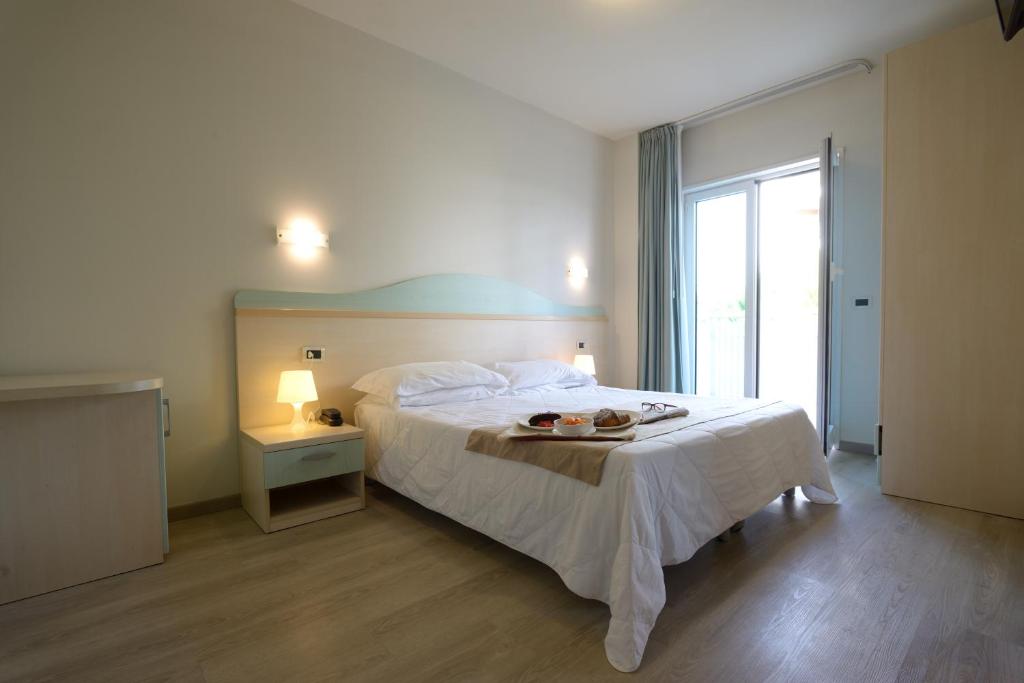 une chambre avec un lit avec un plateau de nourriture dessus dans l'établissement Hotel Salus, à Lignano Sabbiadoro