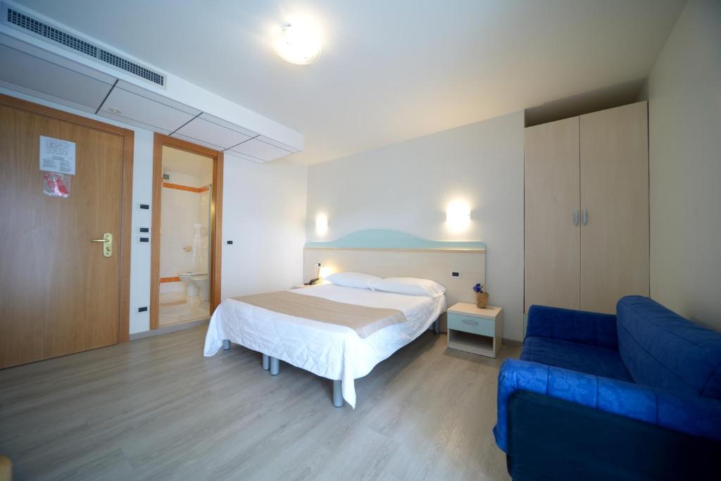 une chambre avec un lit et un canapé bleu dans l'établissement Hotel Salus, à Lignano Sabbiadoro