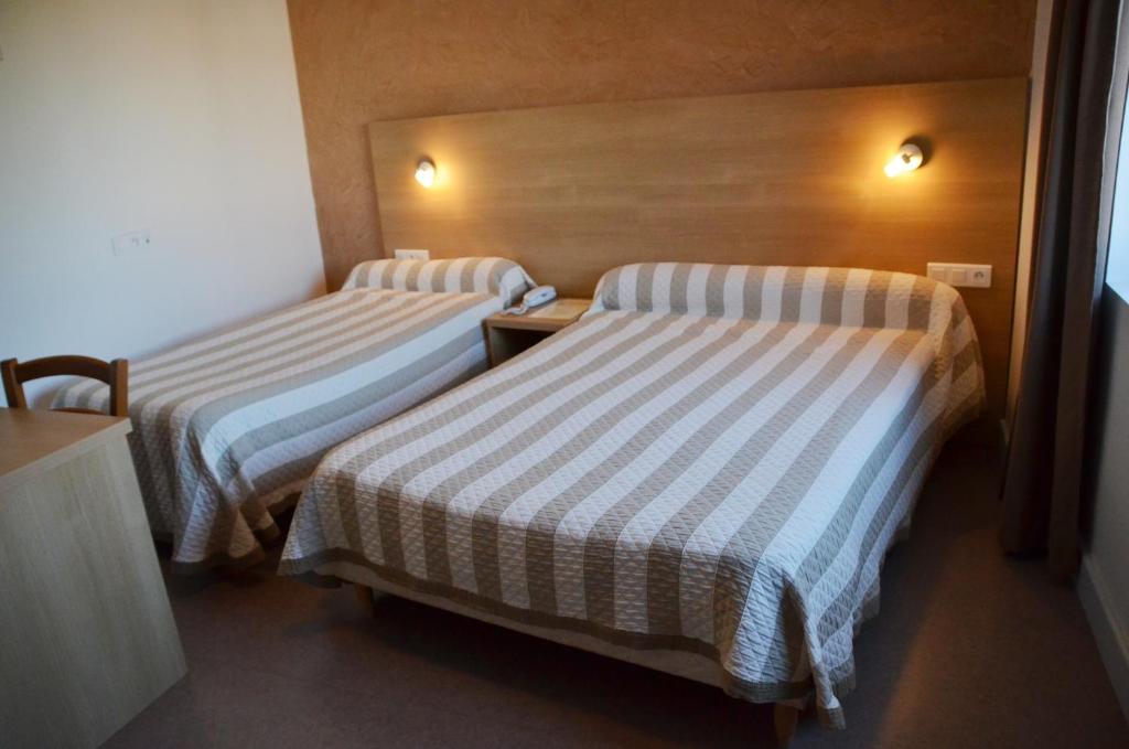 Cette chambre d'hôtel comprend 2 lits avec des draps rayés. dans l'établissement Hôtel de France, à Le Bessat 20 autres photos