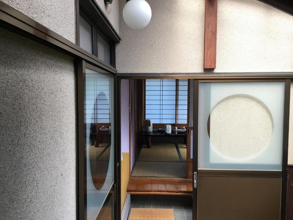 un couloir avec une porte en verre et un miroir dans l'établissement Masugataya Ryokan, à Tako
