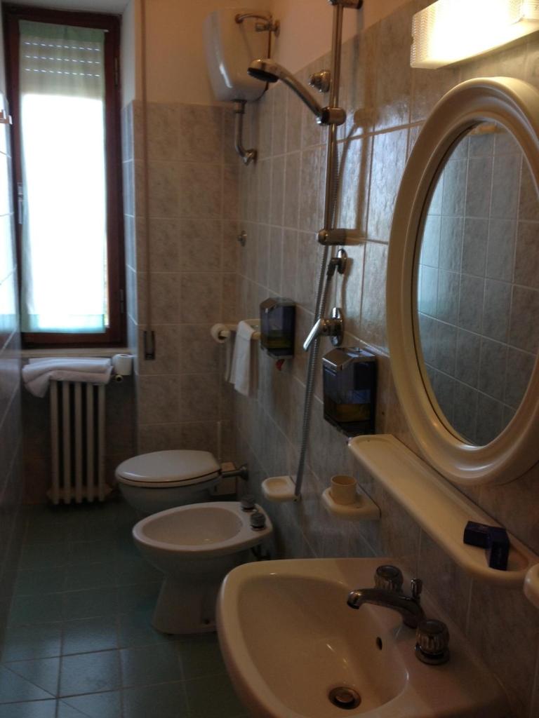 une salle de bain avec un lavabo, des toilettes et un miroir dans l'établissement Hotel Rivamare, à Massignano 46 autres photos