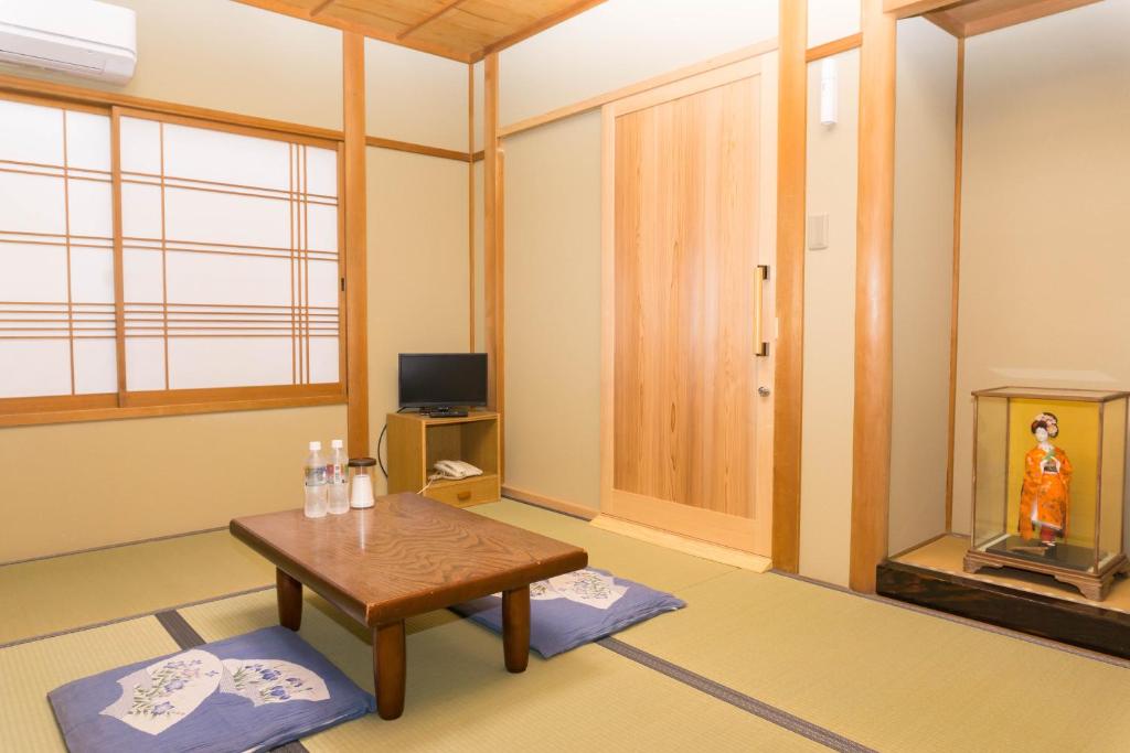 un salon avec une table et une télévision dans l'établissement Ryokan Hinomoto Kyoto Kawaramachi, à Kyoto