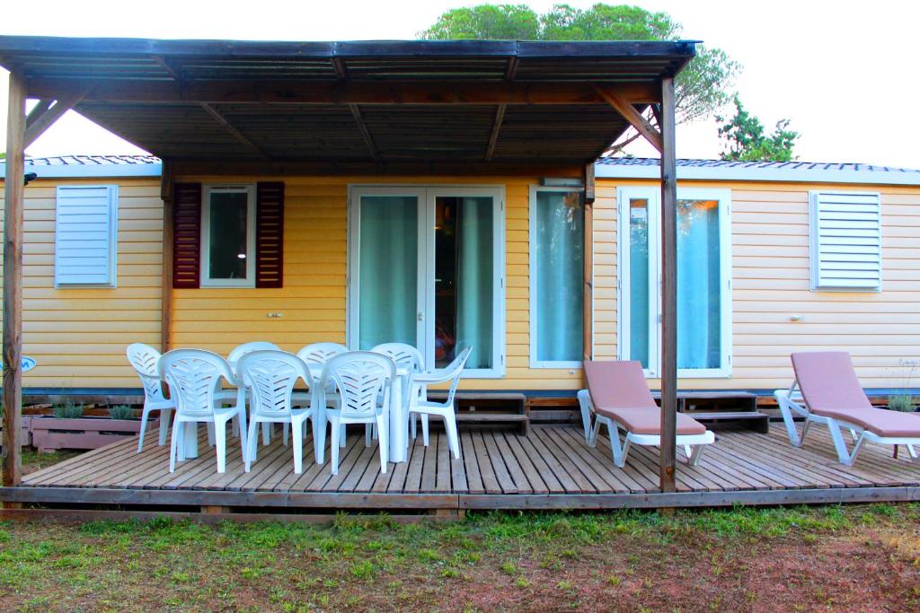 une terrasse avec une table et des chaises ainsi qu'une maison dans l'établissement Mobil home florida - camping les cigales - 5 étoiles, au Muy