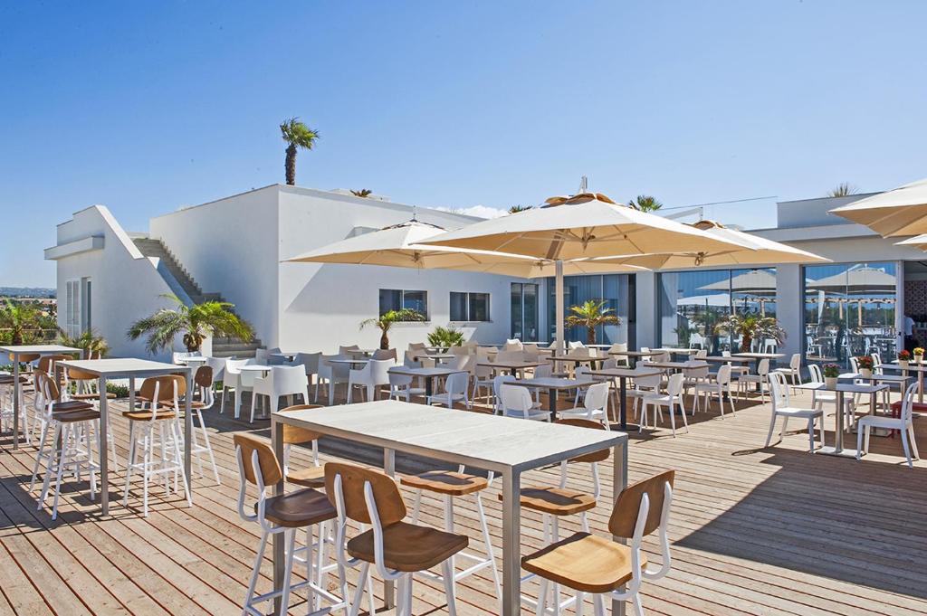 un patio extérieur avec tables, chaises et parasols dans l'établissement Modica Beach Resort, à Marina di Modica