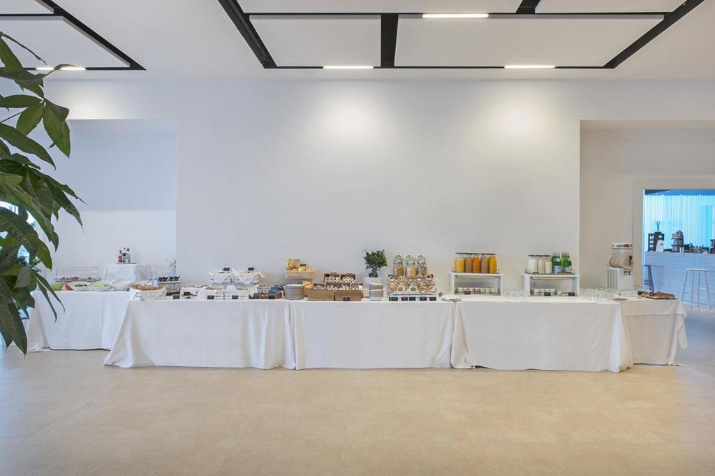 une salle blanche avec des tables blanches et des nappes blanches dans l'établissement Modica Beach Resort, à Marina di Modica 93 autres photos