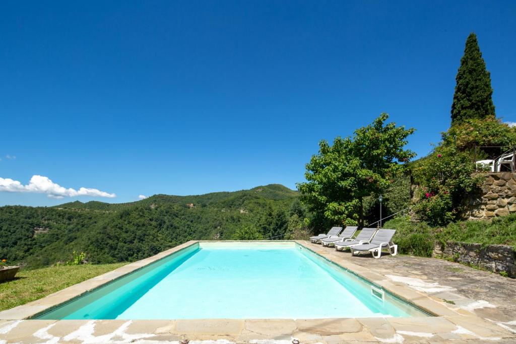 une piscine avec deux chaises longues à côté dans l'établissement Casale Mazzini by VacaVilla, à San Godenzo