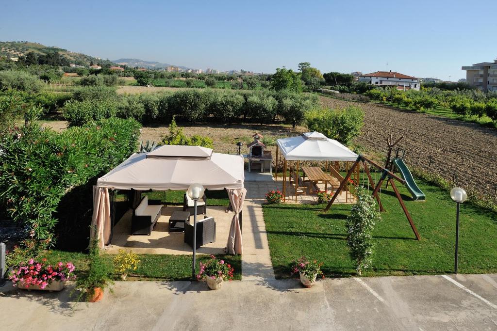 - une vue sur le jardin avec deux parasols et une table dans l'établissement Hotel Lidia, à Alba Adriatica