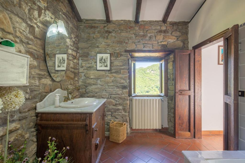 La salle de bains en pierre est pourvue d'un lavabo et d'une fenêtre. dans l'établissement Casale Mazzini by VacaVilla, à San Godenzo