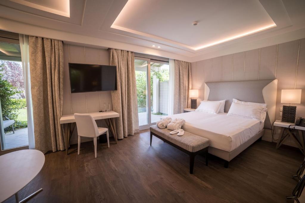 une chambre avec un lit, un bureau et une télévision dans l'établissement Splendido Bay Luxury Spa Resort, à Padenghe sul Garda