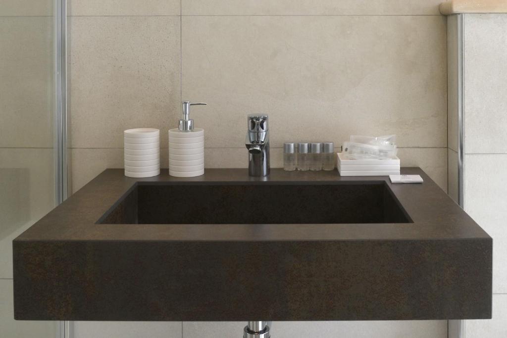 La salle de bains est pourvue d'un lavabo noir et d'un comptoir. dans l'établissement Hotel Villa MIKI, à Bordighera