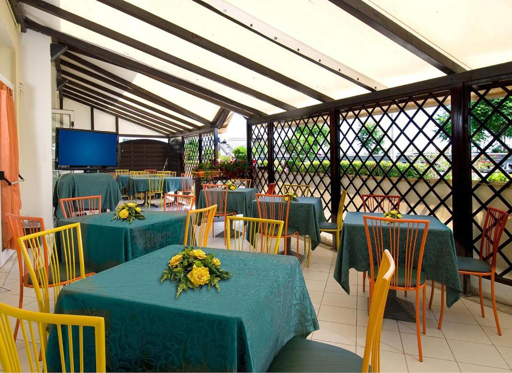 un restaurant avec des tables et des chaises vertes et une télévision dans l'établissement Hotel Ristorante Miramare, à Pesaro