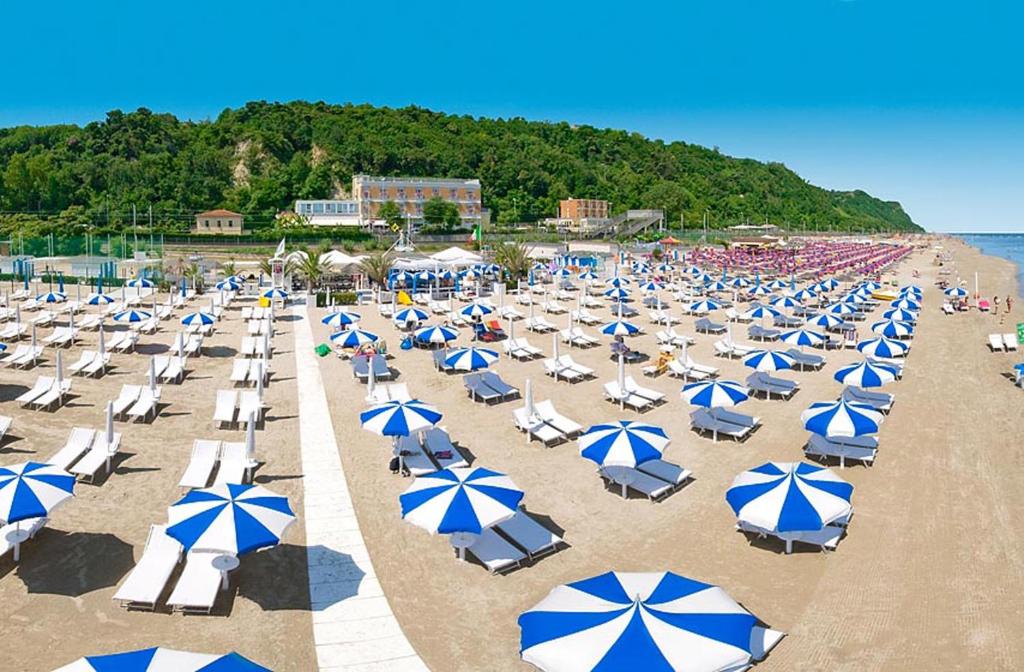 - un bouquet de chaises et de parasols sur une plage dans l'établissement Hotel Ristorante Miramare, à Pesaro