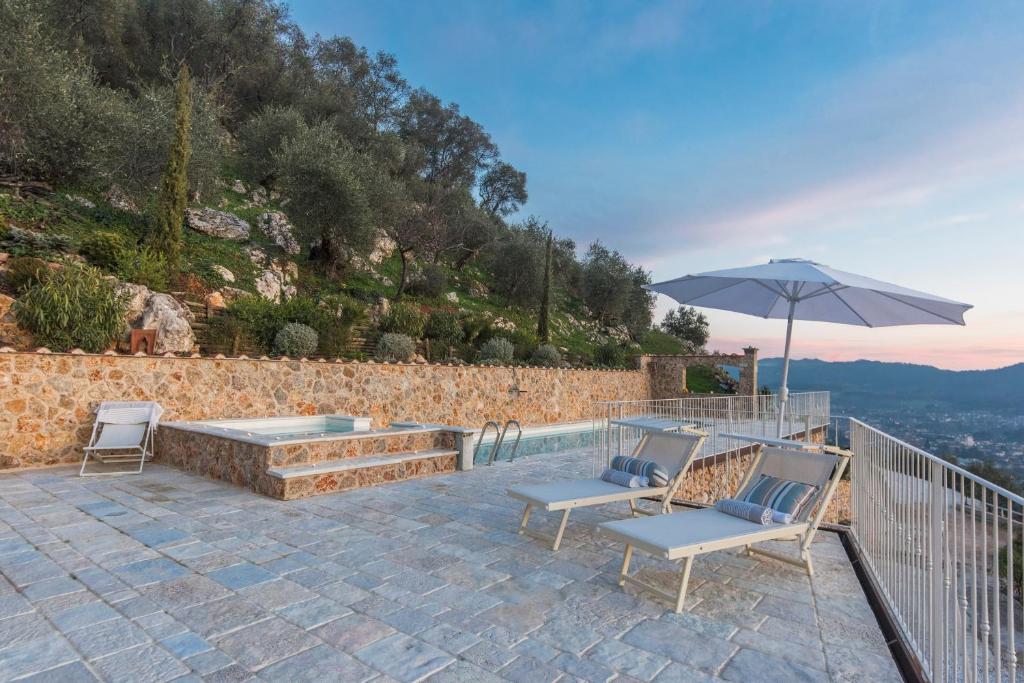 un patio avec deux chaises et un parasol dans l'établissement Charming farmhouse in the hills, private pool, sea view, dream panorama, à Camaiore