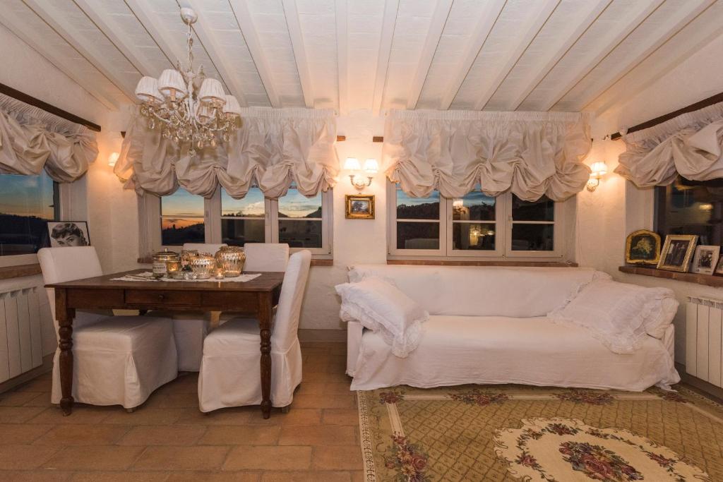 - un salon avec une table, un canapé et des fenêtres dans l'établissement Charming farmhouse in the hills, private pool, sea view, dream panorama, à Camaiore