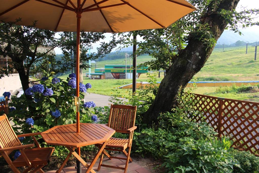 une table et des chaises en bois sous un parasol dans l'établissement Yamakyuso, à Otari