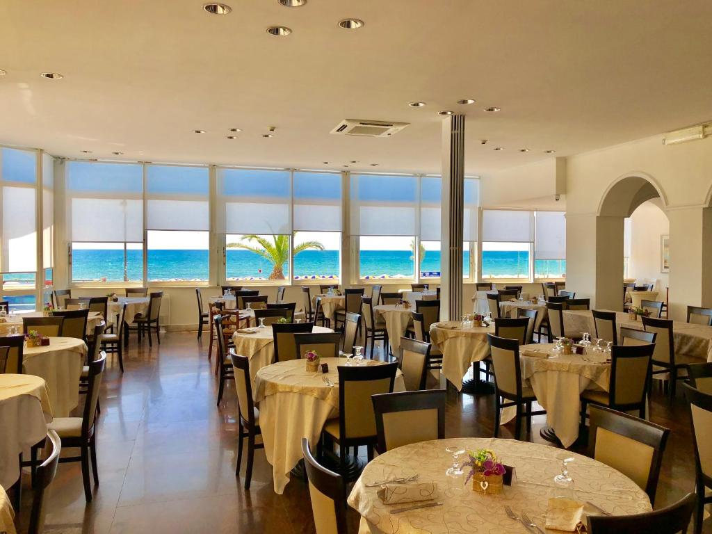 un restaurant avec des tables et des chaises avec l'océan en arrière-plan dans l'établissement Hotel Villa Eleonora, à Scauri