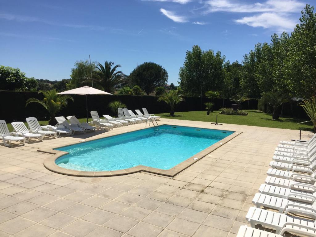 une piscine avec des chaises et un parasol dans l'établissement la ferme des 4 chenes, à Urt