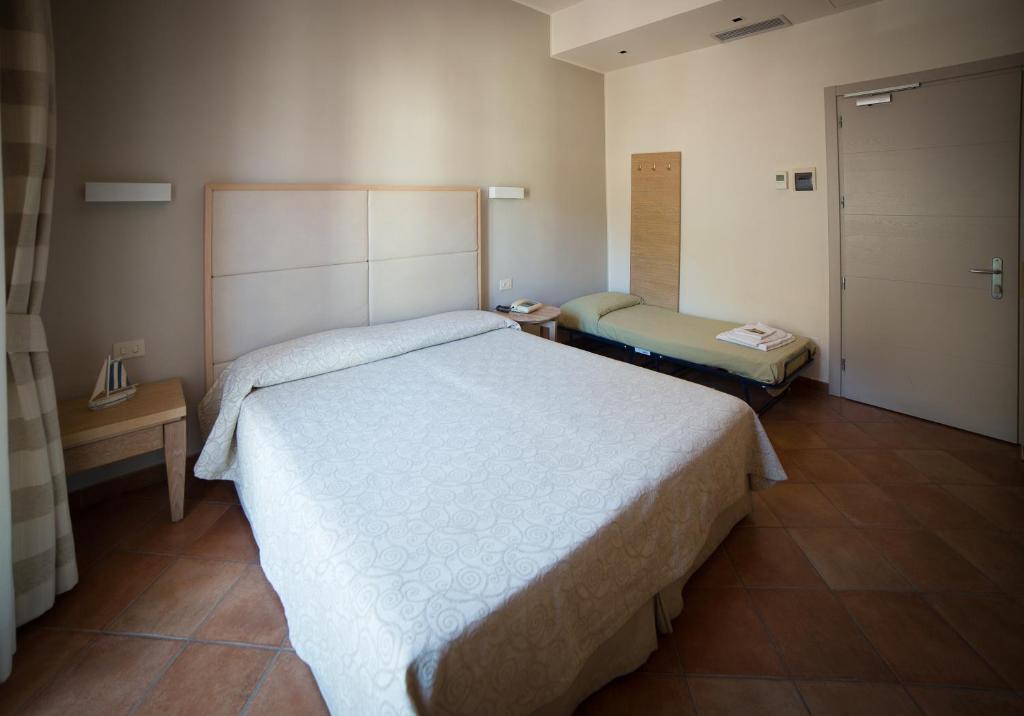 - une chambre avec un grand lit blanc et une porte dans l'établissement Hotel Miramare, à Castiglione della Pescaia