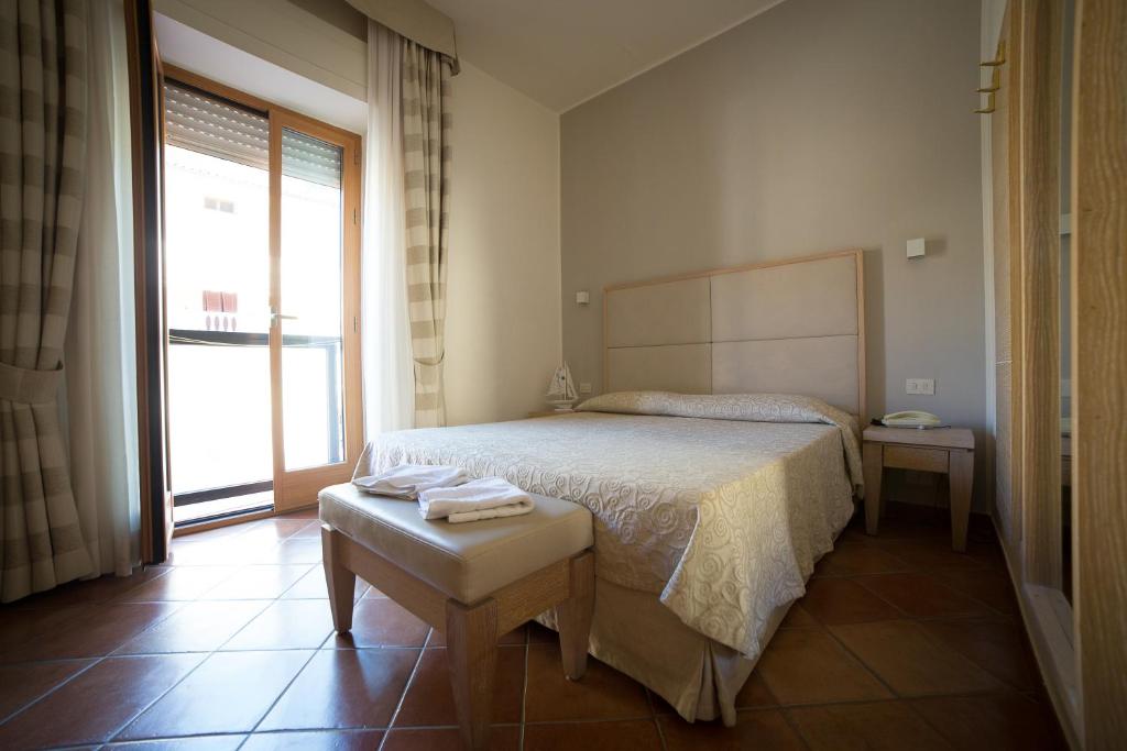 une chambre avec un lit et une grande fenêtre dans l'établissement Hotel Miramare, à Castiglione della Pescaia