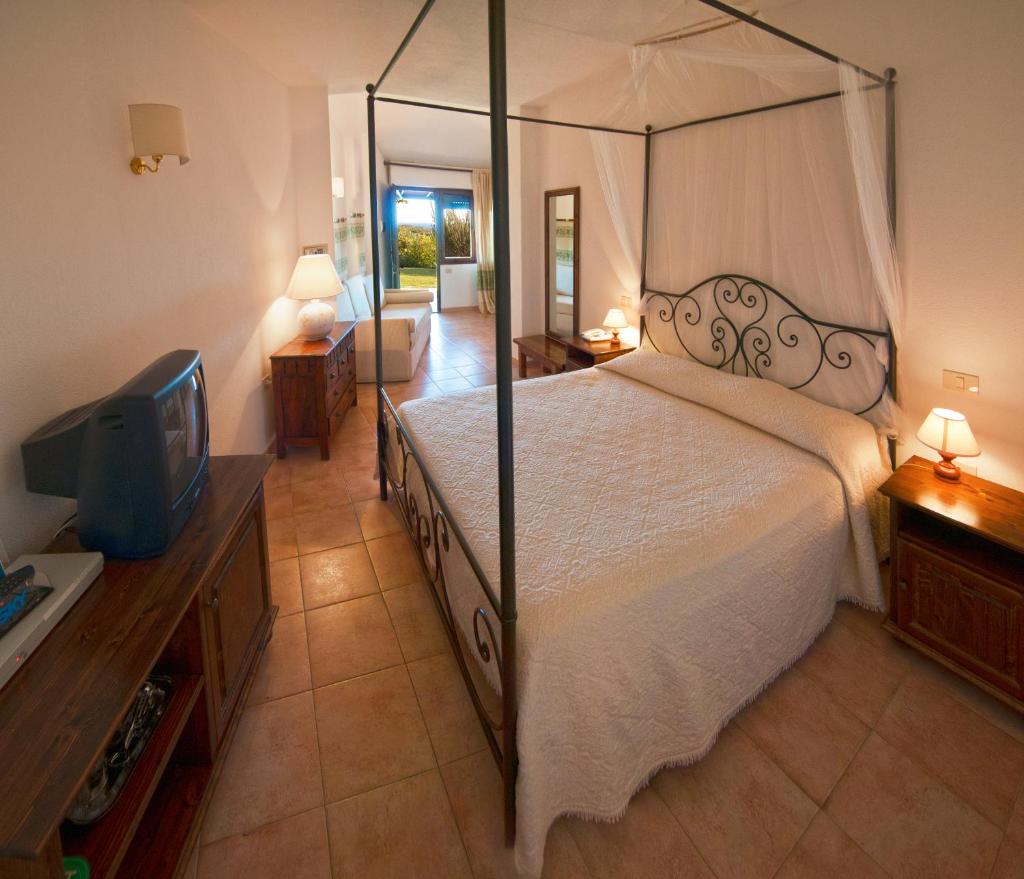 une chambre avec un grand lit et une télévision dans l'établissement Hotel Spartivento, à Chia