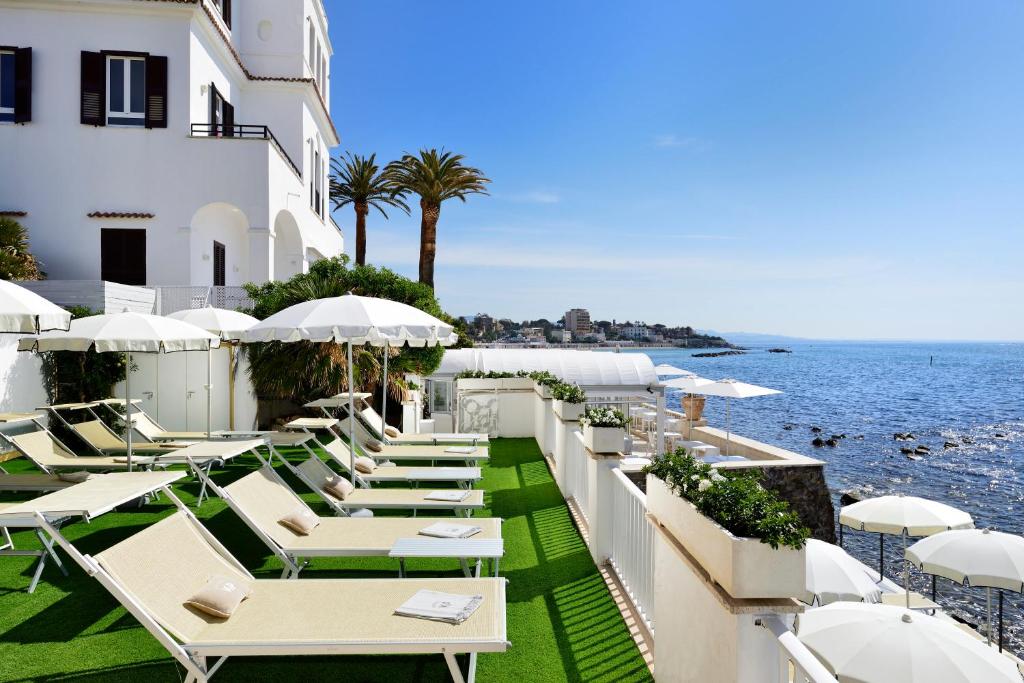 une rangée de tables et de chaises à côté de l'océan dans l'établissement Villa delle Palme, à Santa Marinella