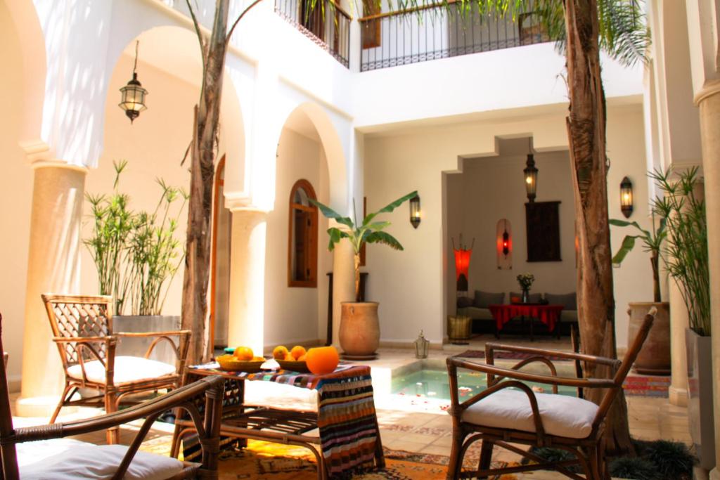 un salon avec une table et des chaises et une piscine dans l'établissement Riad Mariana, à Marrakech