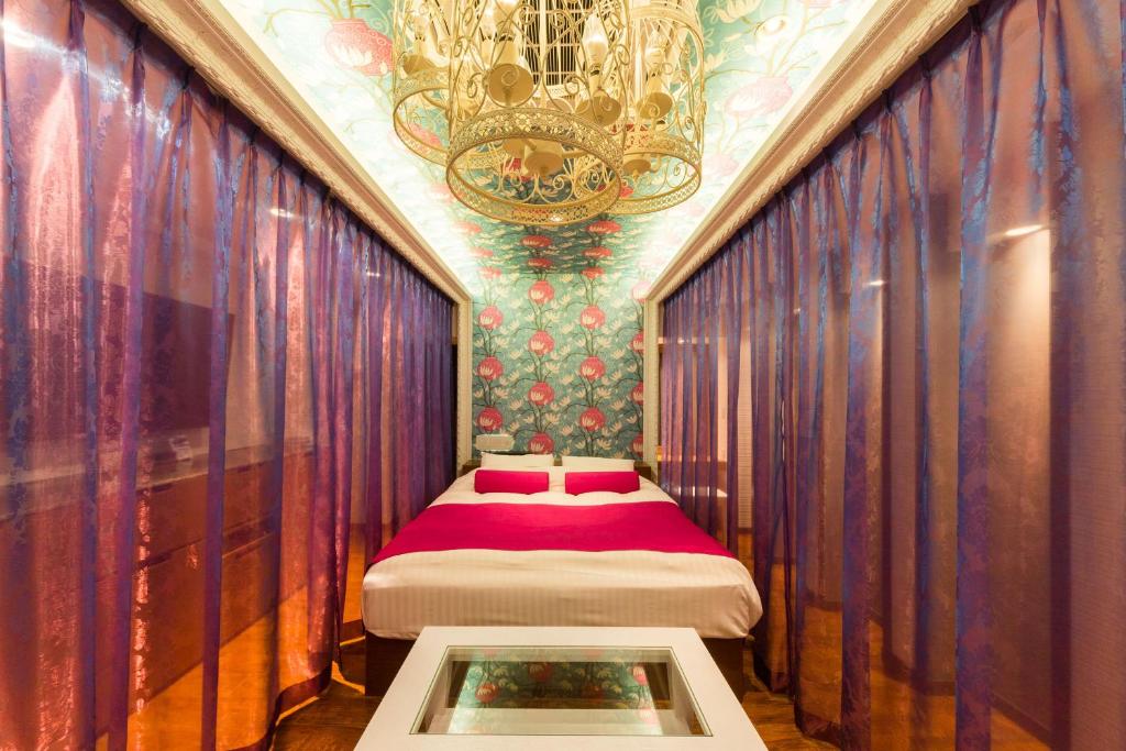 - une chambre avec un lit et un lustre dans l'établissement Hotel CLover Leaf Tsukasa (Love Hotel), à Tosu