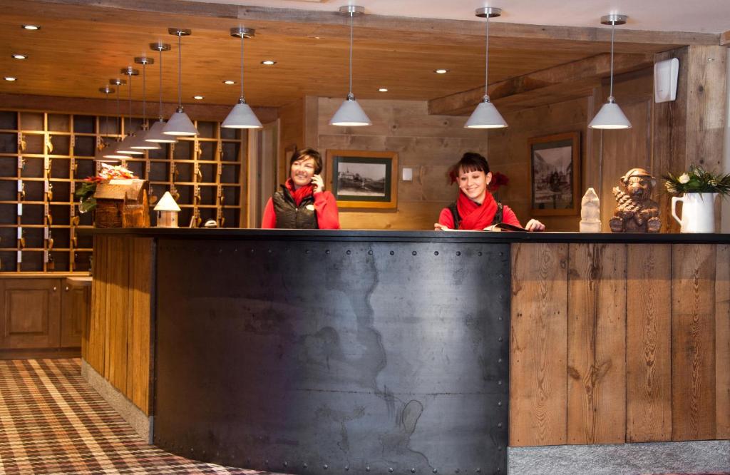 Deux femmes se tenant derrière un bar dans un restaurant dans l'établissement Chalet-Hôtel La Marmotte, La Tapiaz & SPA, The Originals Relais, aux Gets 37 autres photos