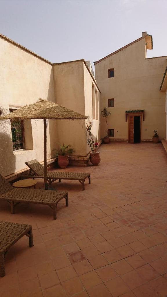 une cour vide avec des bancs et un parasol dans l'établissement Riad jasmins & Spa, à Fès