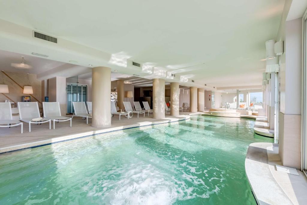 - une piscine dans un hôtel avec des chaises blanches dans l'établissement Villa Maria Hotel & SPA, à Francavilla al Mare