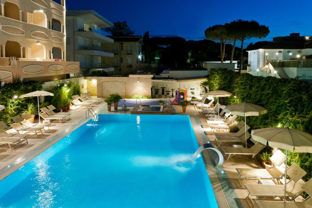 - une piscine avec chaises longues et parasols la nuit dans l'établissement Hotel Derby Exclusive, à Milano Marittima