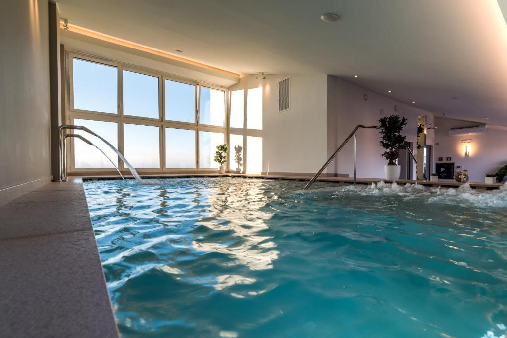 une grande piscine avec de l'eau bleue dans un immeuble dans l'établissement Hesperia Hotel & Residence, à Lido di Jesolo