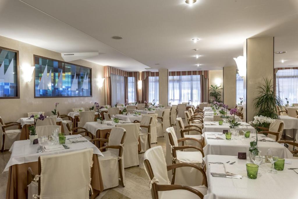 - une salle de banquet avec des tables et des chaises blanches dans l'établissement Hotel Du Lac et Bellevue, à Bardolino