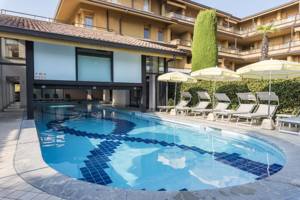 - une piscine en face d'un bâtiment avec des parasols dans l'établissement Hotel Du Lac et Bellevue, à Bardolino