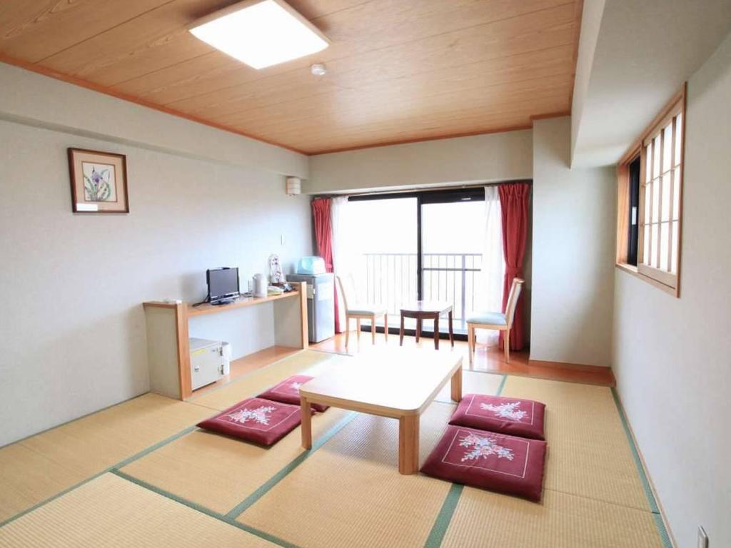 - un salon avec une table et des coussins rouges dans l'établissement Hotel New Koyo, à Kusatsu