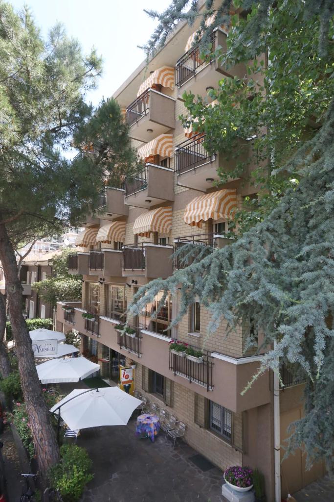 un grand bâtiment avec des parasols devant lui dans l'établissement Hotel Marselli, à Rimini