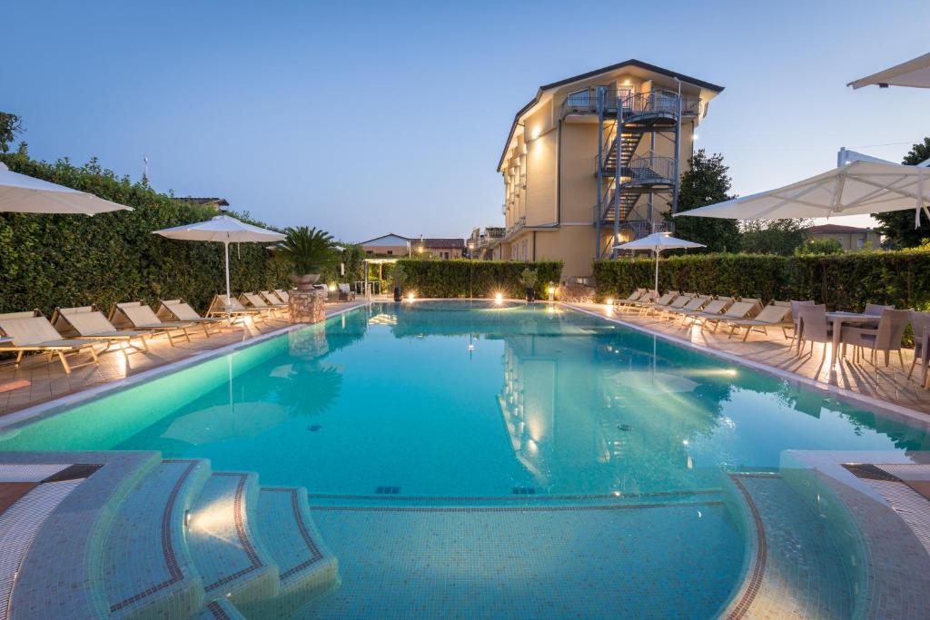 une grande piscine avec chaises et parasols dans l'établissement Hotel Villa Tiziana, à Marina di Massa