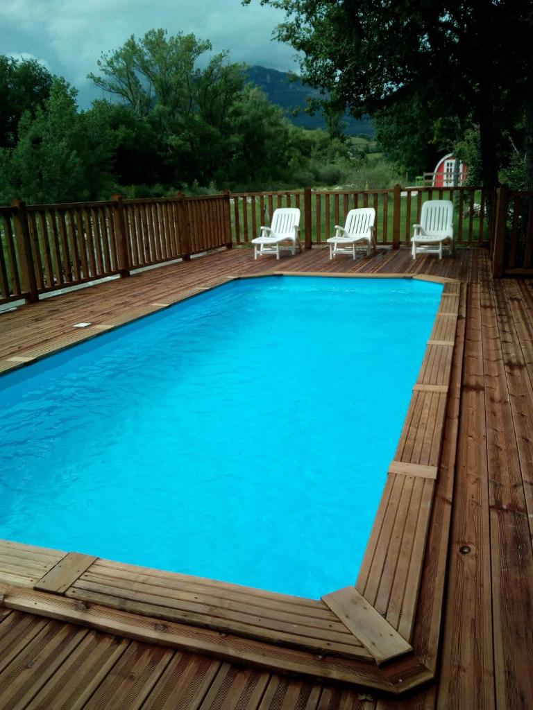 une grande piscine bleue sur une terrasse en bois dans l'établissement Camping du Moulin de Thoard, à Thoard