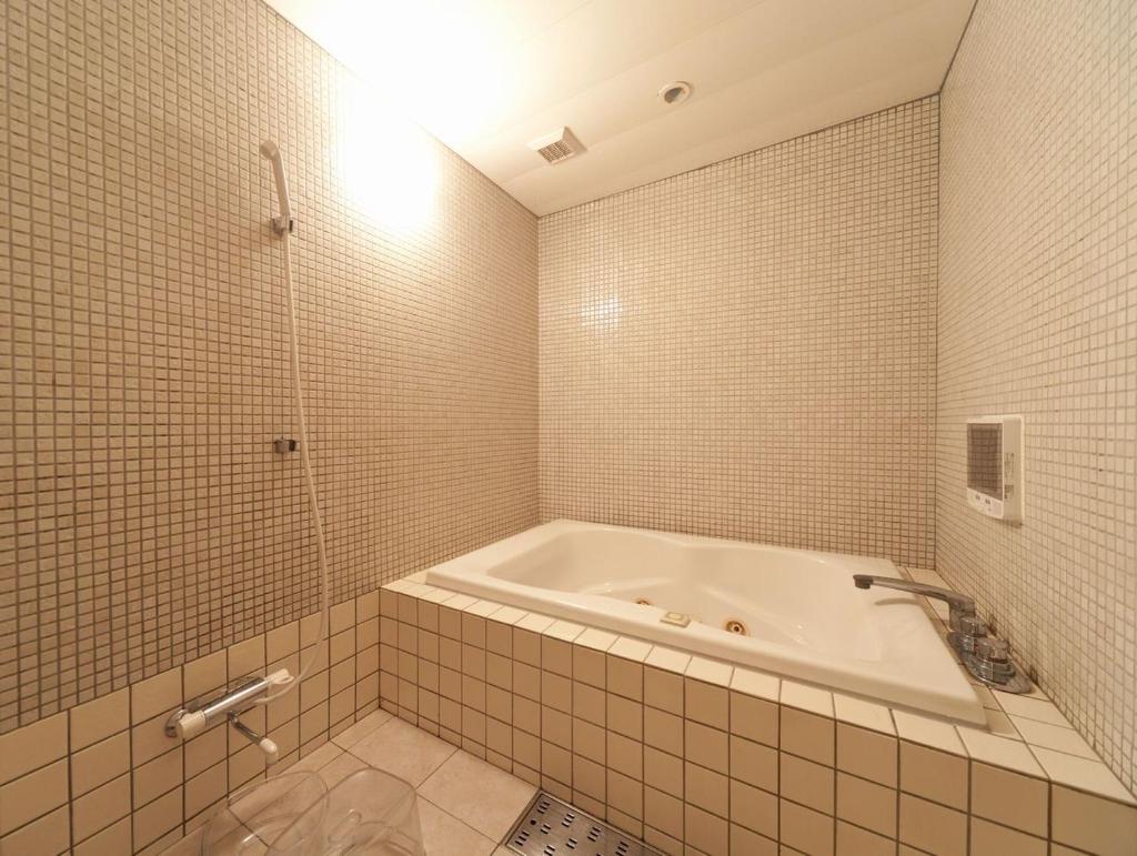 une salle de bain blanche avec une baignoire et une douche dans l'établissement ホテルファインシエル島根松江店 - 大人専用, à Matsue