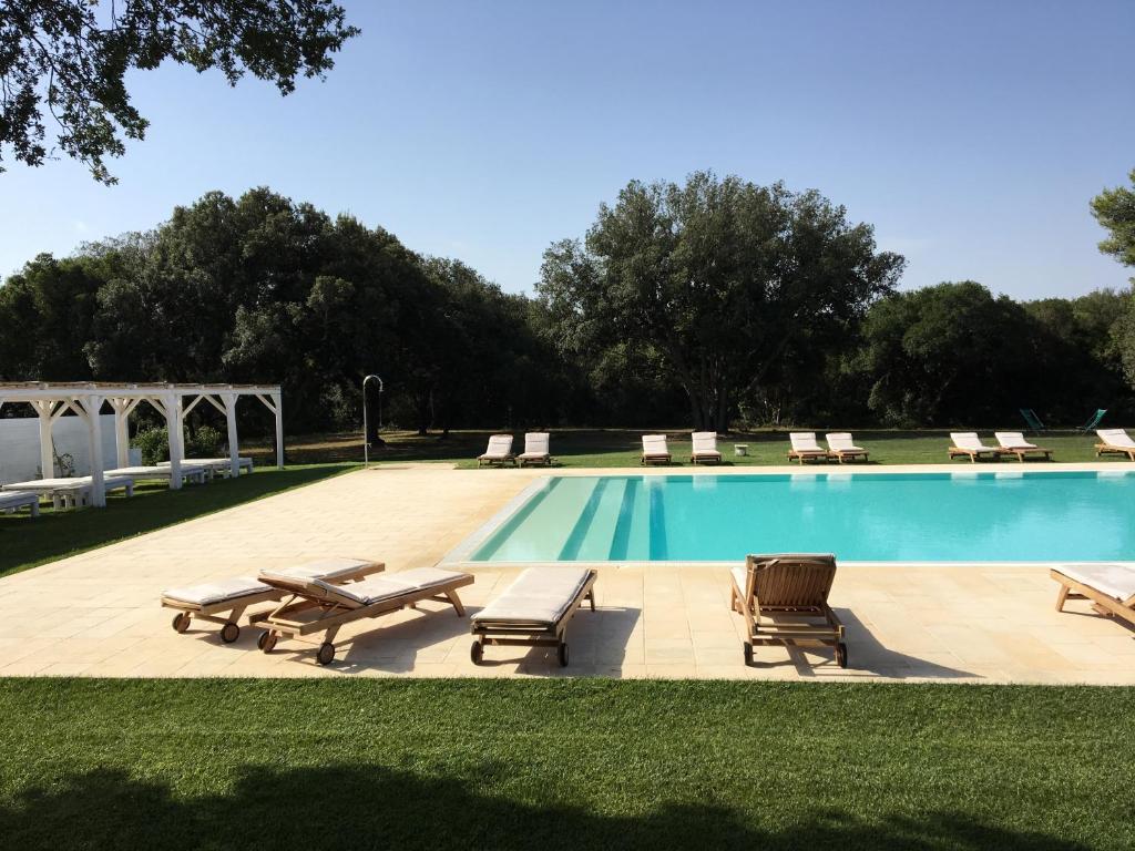 une piscine avec des chaises longues et des transats à côté dans l'établissement Residence Altair - Serra degli Alimini, à Otrante